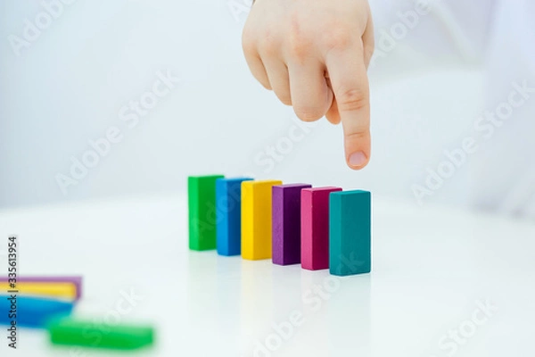Fototapeta Building items in a single row. Concept of diagnostics of children's autism. A child plays with a colored wooden construction tool. Close.