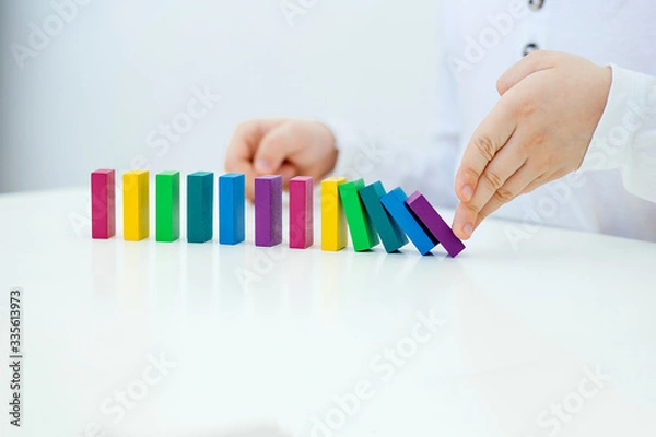 Fototapeta Building items in a single row. Concept of diagnostics of children's autism. A child plays with a colored wooden construction tool. Close.