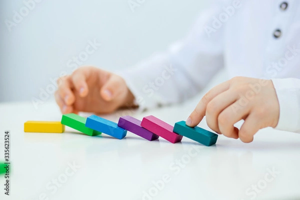 Fototapeta Building items in a single row. Concept of diagnostics of children's autism. A child plays with a colored wooden construction tool. Close.