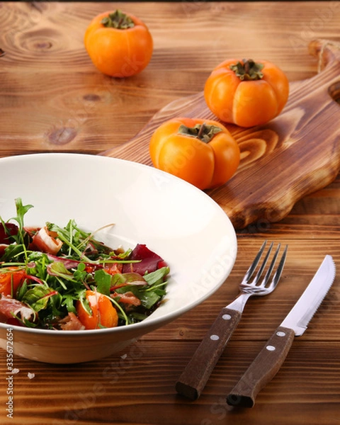 Fototapeta persimmon with meat and persimmon and red wine on wooden table. microgreen and ingredients