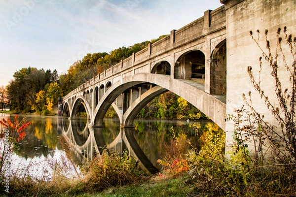 Fototapeta Abandoned bridge reflected into Lake Ontelaunee in autumn