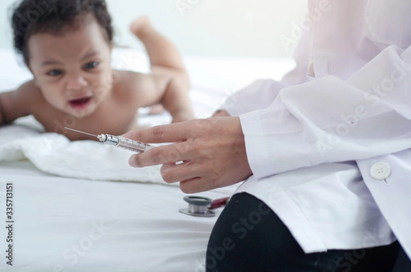 Fototapeta Doctor holds an injection syringe for baby  , Dark skinned baby looking at doctors and crying, selective focus