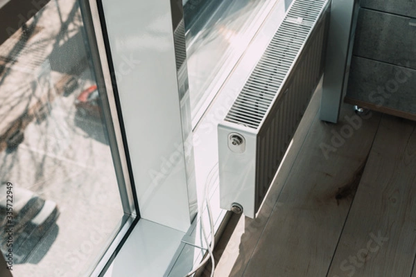 Fototapeta white radiator battery in the office near the window.