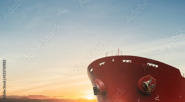 Obraz Close up of large red merchant crago ship in the ocean underway. at sunrise or sunset .Performing cargo export and import operations.