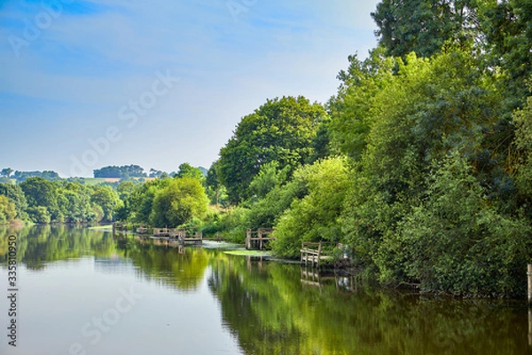 Fototapeta Image of the La vilaine River with trees and timber fishing platforms