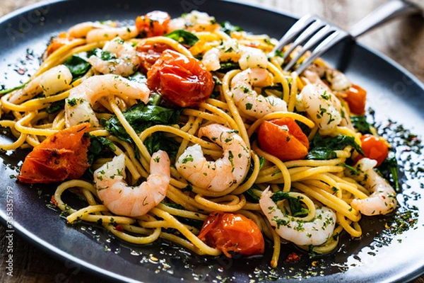 Fototapeta Spaghetti with prawns and vegetables on wooden background