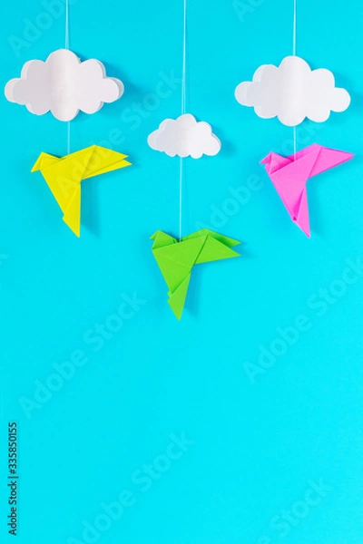 Fototapeta blue background with colorful birds and white clouds on a rope of paper