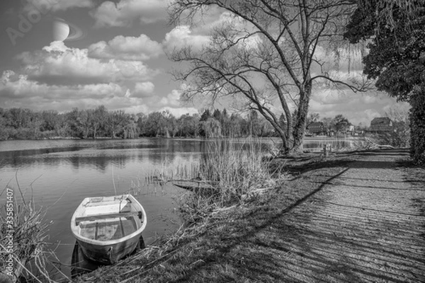 Fototapeta rowing boat is moored on the shore of a small lake in fine weather