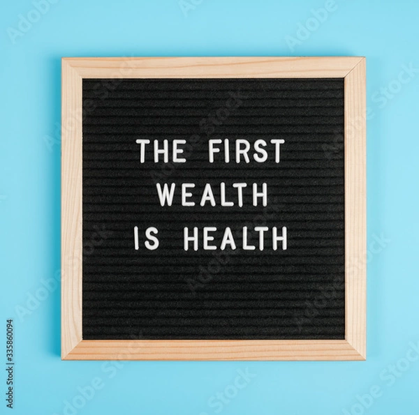 Obraz Pierwszym bogactwem jest zdrowie. Motywacyjny cytat na czarnej tablicy na niebieskim tle. Concept Health Care and Medicine, inspirujący cytat dnia