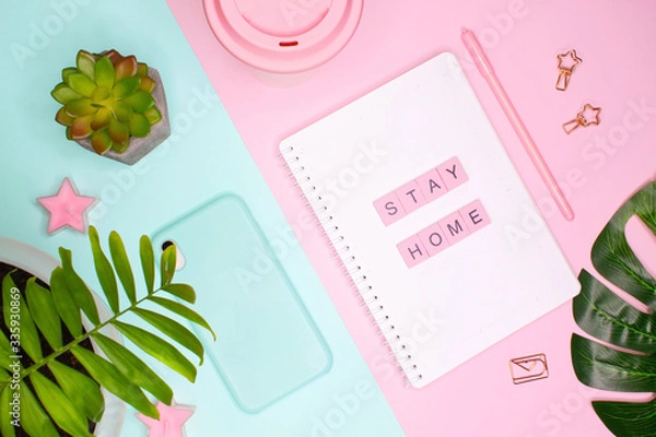 Fototapeta Concept flat lay. Words "STAY HOME" made of wooden letters on notepad and palm leaves