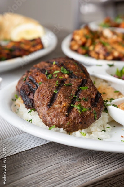 Fototapeta A view of several Mediterranean dishes in a restaurant or kitchen setting, featuring kafta and shish kebob.