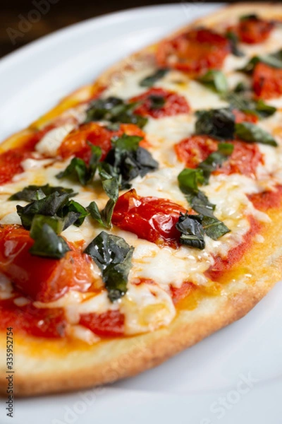 Fototapeta A view of a plate of margherita style flatbread pizza, in a restaurant or kitchen setting.