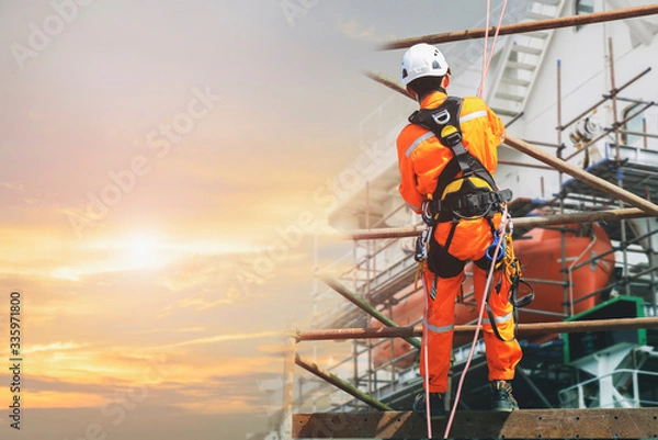 Obraz Double exposure worker on height at scaffolding in construction site symbol foot for building, wearing equipment protective full safety harness with safety helmet and PPE.