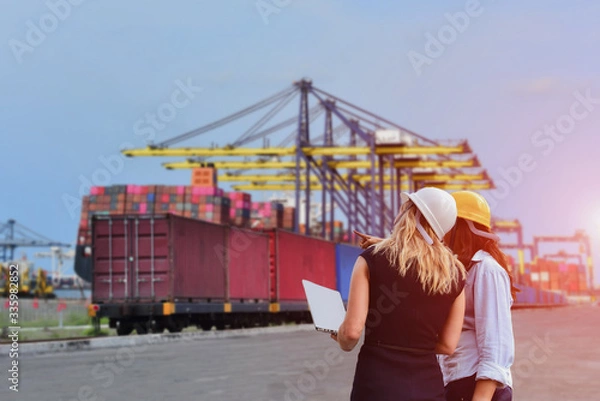 Fototapeta woman engineer worker inspect container with computer box on train platform in port cargo freight for import export shipping with crane bridge in harbor background