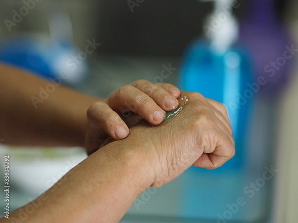 Fototapeta woman is standing with the finger to rub the gel alcoholic 70 percent mixture with gelatin on the back of the hand to prevent germs protect corona virus, covid19, hand Sanitizer