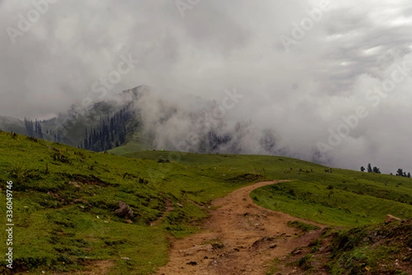 Fototapeta Muddy road in the mountains with clouds