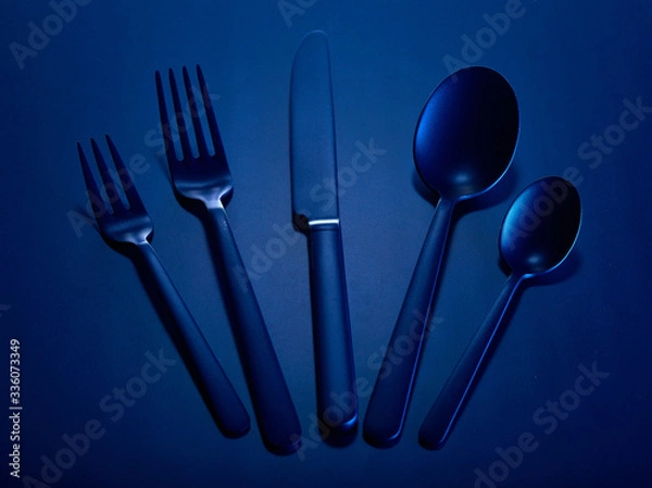 Fototapeta Blue set of kitchen appliances knife, spoons and forks in a group on a blue beautiful background. You can change the color.