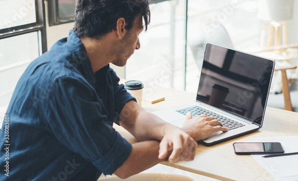 Obraz Man working on laptop at bright studio