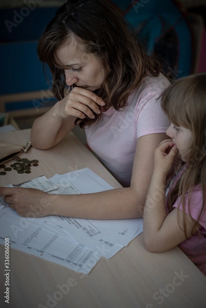 Fototapeta Small family. Single mother has financial problems. Her little daughter calms down sad mother.