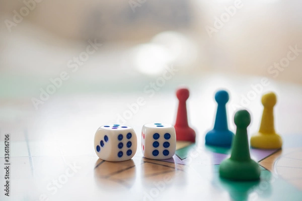 Fototapeta Colorful, bright game chips stand on a game Board with playing cubes: the concept of Board games, the background, games at home, a place for text