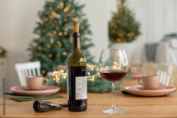 Fototapeta Bottle of red wine and a glass on the background of the Christmas tree