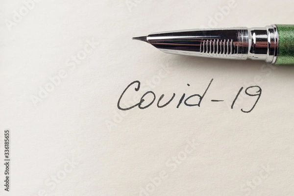 Fototapeta Covid-19 coronavirus inscription on a blank empty sheet of paper in a notebook. Nearby lies a pen. A lot of space for inscriptions and copyspace. Blank for inscriptions. Template for article or cover.
