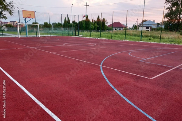 Fototapeta Outdoors mini football and basketball court with ball gate and basket surrounded with high protective fence.