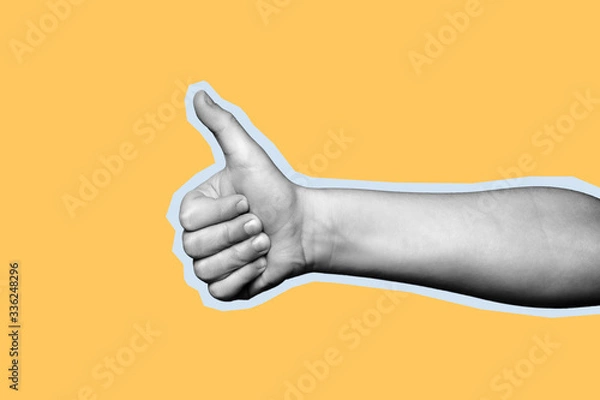 Fototapeta Child hand shows thumb up on yellow background. Paper cut style.