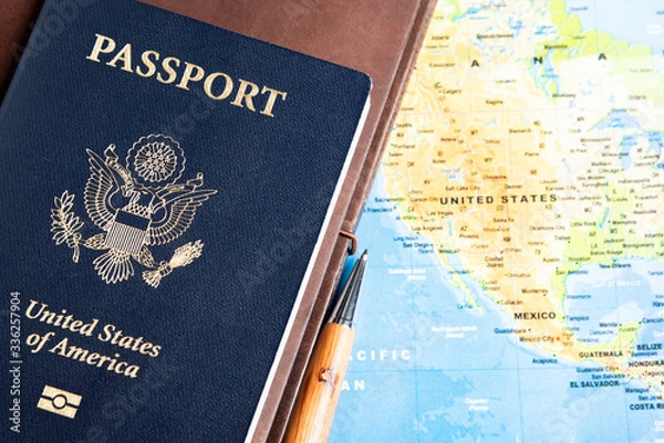 Fototapeta The foil-stamped dark blue front cover of an American passport set on a world map background.