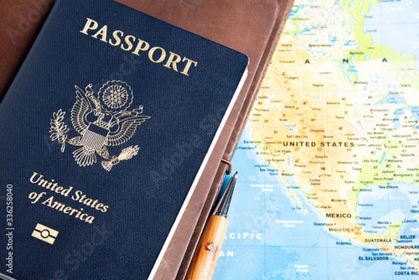 Fototapeta The foil-stamped dark blue front cover of an American passport set on a world map background.