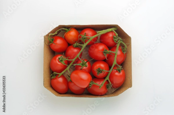 Obraz Cocktail tomatoes on the branches lie in a cardboard box. Light gray background. View from above.