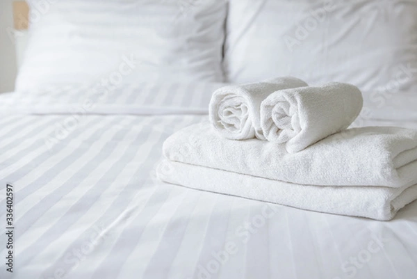 Fototapeta Freshly laundered fluffy towels on bed in hotel