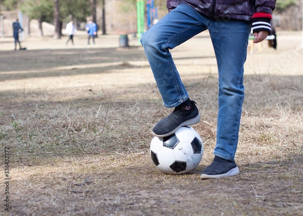 Obraz a boy in a red hood plays soccer with a soccer ball on the street