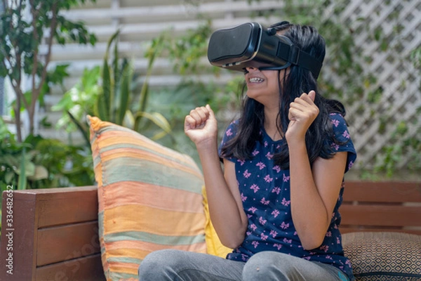 Fototapeta Indian Asian girl viewing through a Virtual Reality device, experiencing immersive technology