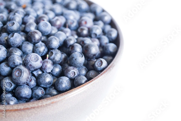 Fototapeta Fresh bilberry in a bowl on a white surface, close-up

