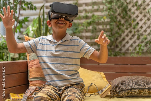 Fototapeta Indian Asian boy viewing through a Virtual Reality device, experiencing immersive technology