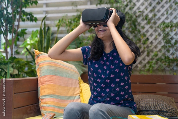 Fototapeta Indian Asian girl viewing through a Virtual Reality device, experiencing immersive technology