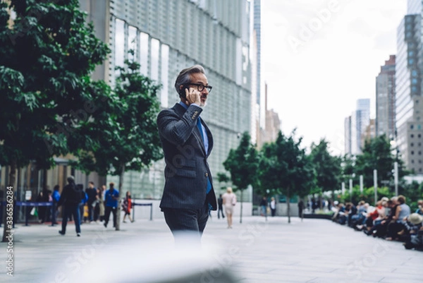 Fototapeta Mature businessman calling by smartphone in city
