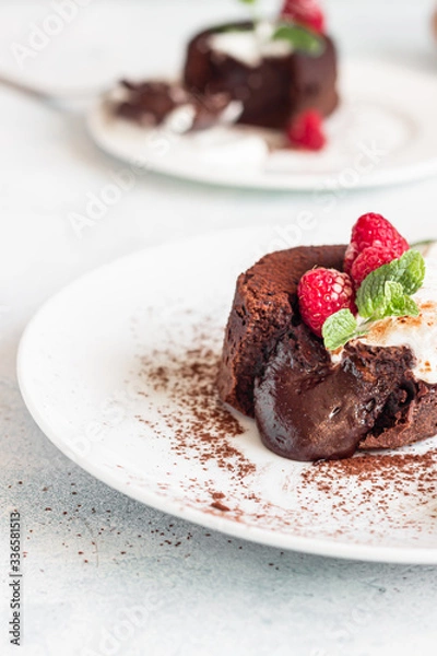 Fototapeta Delicious chocolate fondant or lava cake with cream, raspberries and cream, light grey concrete background. Hot chocolate dessert (pudding) with liquid center. Fondant au chocolate. 