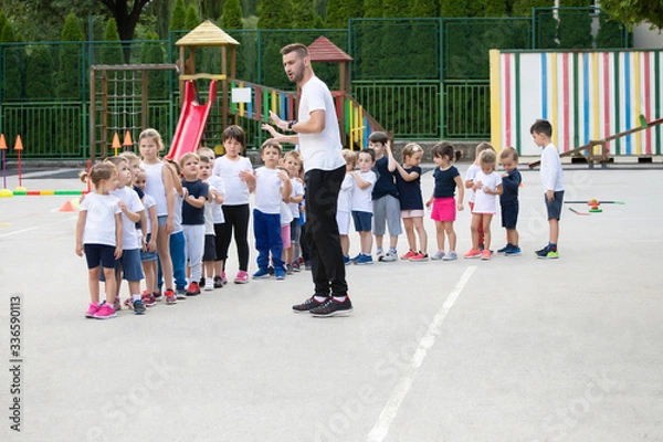 Fototapeta Group of children standing in column and waiting for lesson start.  Sport school