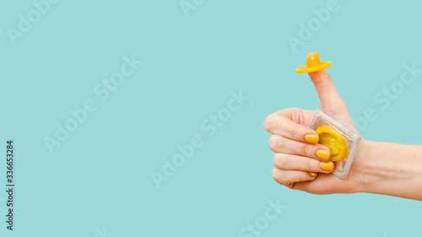Obraz Woman holding a yellow condom on her finger