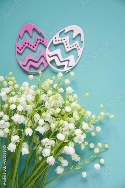 Fototapeta Floral blue background with fresh flowers. Spring greeting card for Easter. A bouquet of lily of the valley and a gift, eggs