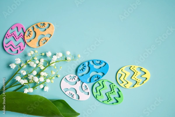 Fototapeta Floral blue background with fresh flowers. Spring greeting card for Easter. A bouquet of lily of the valley and a gift, eggs