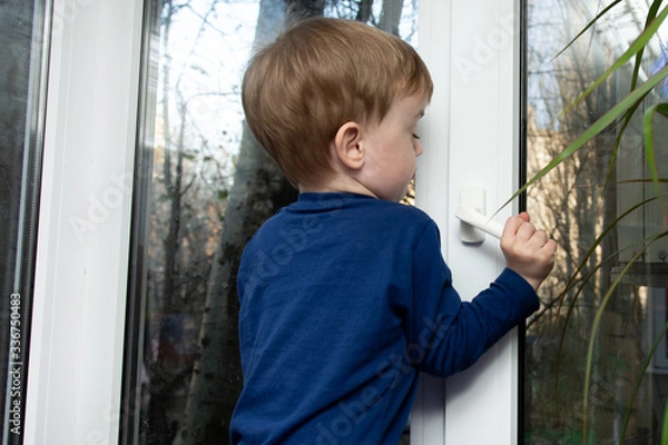 Fototapeta little boy is trying to open the window. danger of falling