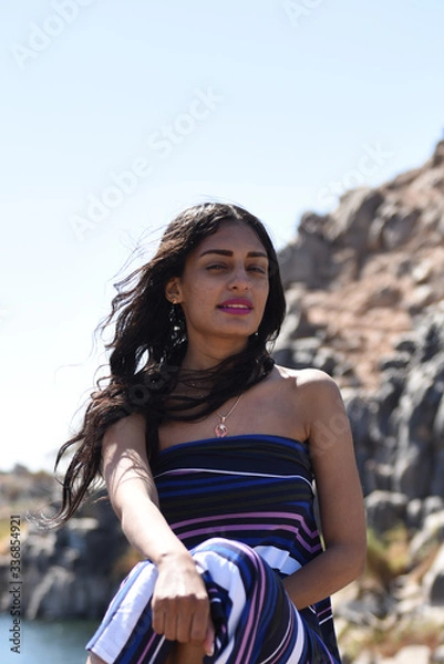 Fototapeta middle eastern  girl on a mountain river sitting on a large stone
