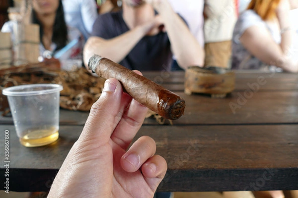 Fototapeta Cigar completed and smoking, accompanied with a cup of liquor
