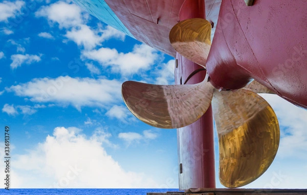 Obraz Propeller of a boat Navy close up, with rudder at stern ship after maintenance, repair already on blue sky background in shipyard.
