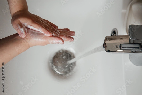 Fototapeta Baby washes his hands qualitatively with soap in the sink