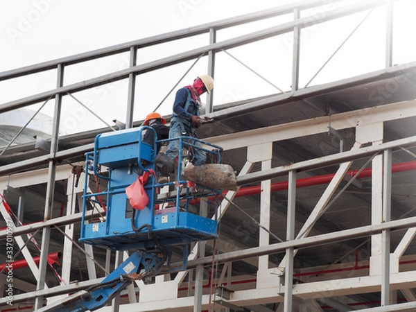 Obraz construction worker at construction site using lifting boom machinery