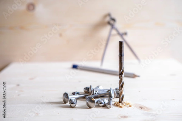 Obraz A drill, screws and a circle and pensil in the background placed on wooden board